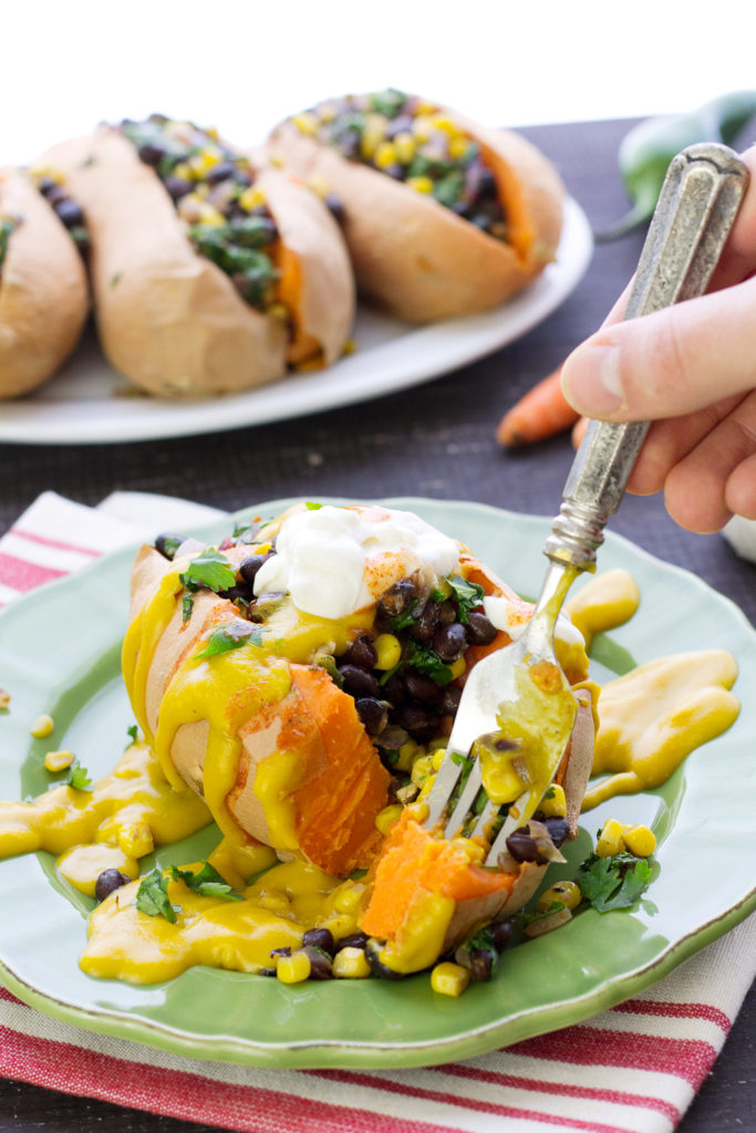 cutting into vegan stuffed sweet potatoes with black beans and kale