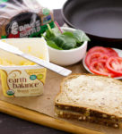 adding vegan butter to vegan blt grilled cheese sandwich