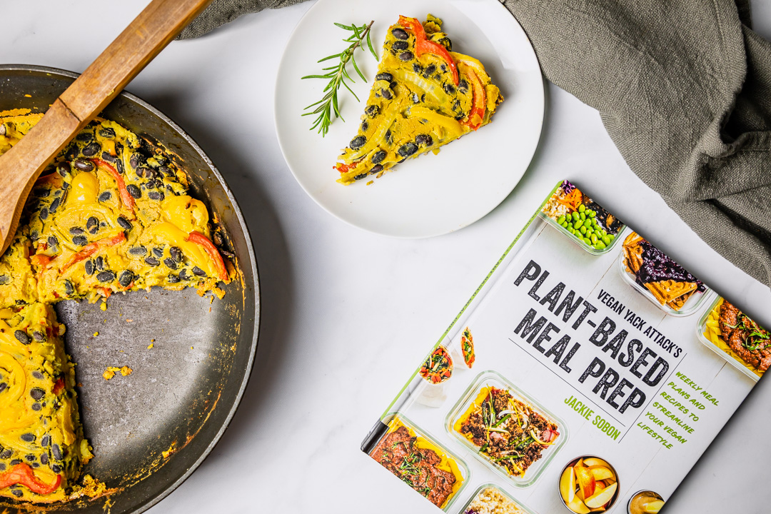 Overhead of vegan hash brown crusted frittata next to vegan yack attacks plant-based meal prep cookbook