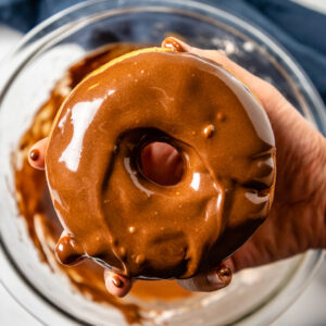 Fingers dipped in chocolate glaze for vegan doughnut recipe
