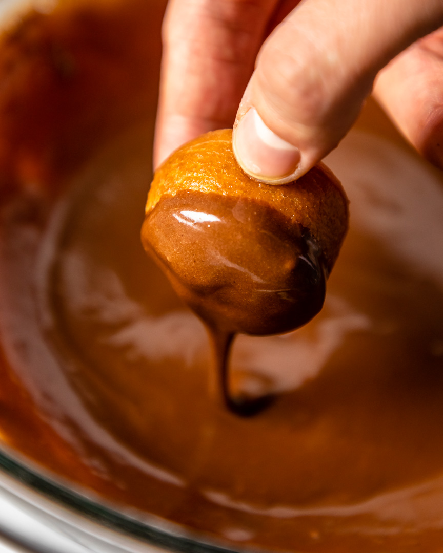 Dipping donut hole in chocolate icing